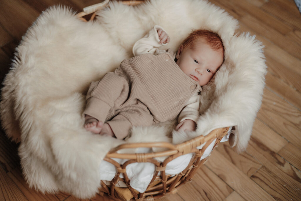 Neugeborenes Baby liegt ruhig in einem weichen Körbchen mit Fellunterlage