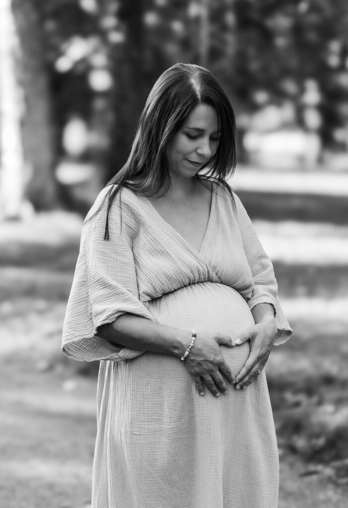 Schwangere Frau hält liebevoll ihren Babybauch in einer emotionalen Schwarzweißaufnahme