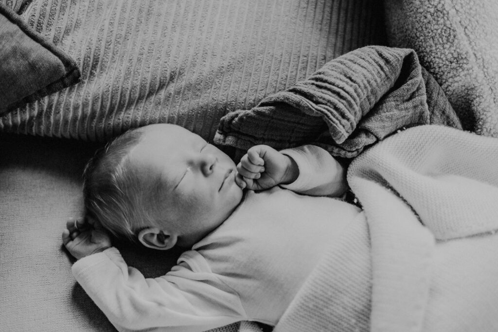 Schlafendes Neugeborenes liegt entspannt eingekuschelt in einer weichen Decke