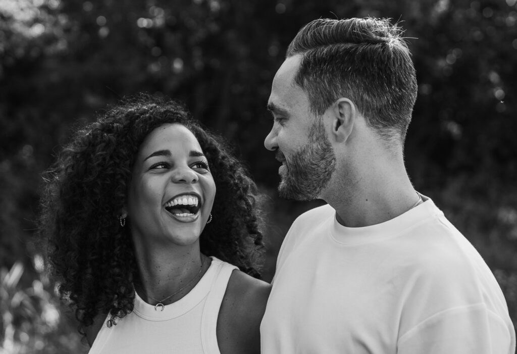 chwarzweißaufnahme eines Paares, das sich lachend ansieht und einen echten Moment teilt