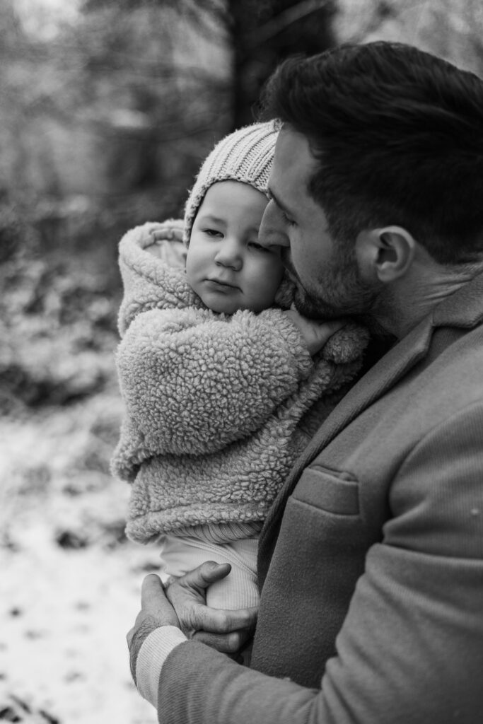 Vater hält sein Kind liebevoll im Arm bei einem winterlichen Familienshooting im Saarland.